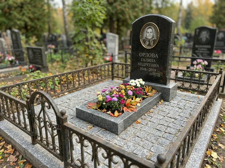 Благоустроенное захоронение с гранитной плиткой, оградой и цветником в Барнауле
