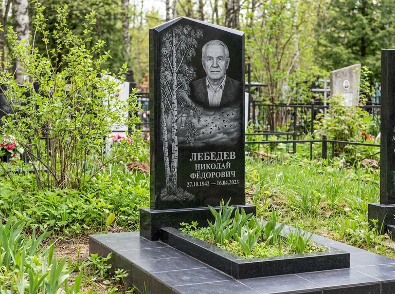 Памятник с гравировкой берёзы: вертикальная стела со скошенным верхом — берёза и стая птиц в небе, гранитный цоколь с тёмной плиткой, работа «Лебедев» в Барнауле