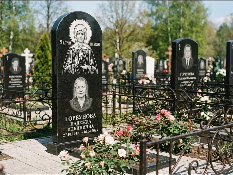 Памятник с гравировкой иконы: стела с арочным верхом и киотом под образ — гравировка образа Матроны Московской, гранитный цоколь с тёмной плиткой, работа «Ковалёв» в Барнауле