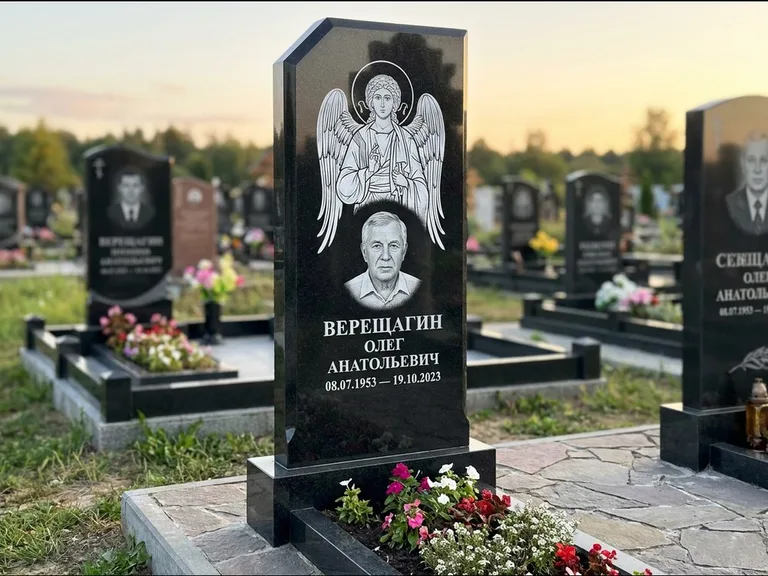 Памятник с гравировкой иконы: стела с резным навершием и нимбом в золоте — гравировка образа Спасителя, высокие разросшиеся туи полукругом, работа «Мельникова» в Барнауле