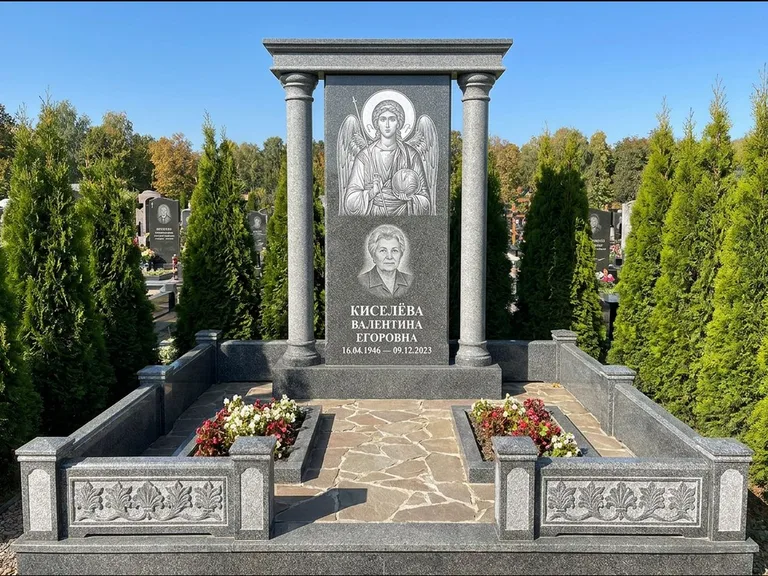 Памятник с гравировкой иконы: массивная стела с двускатным навершием-домиком — гравировка Николая Чудотворца, живая изгородь из туи, работа «Журавлёв» в Барнауле