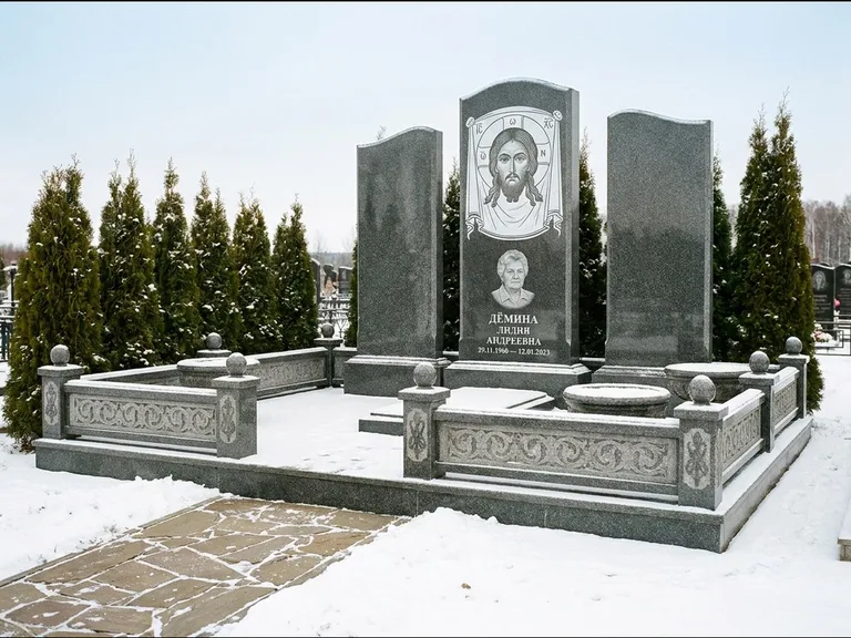 Памятник с гравировкой иконы: узкая вертикальная стела-пилон с ликом — икона в резной рамке-киоте, открытая лужайка без ограды, работа «Одинцов» в Барнауле