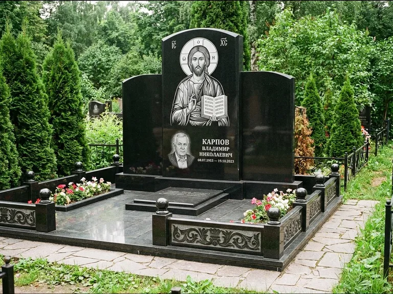 Памятник с гравировкой иконы: широкая панорамная стела с золочёным нимбом — гравировка образа Матроны Московской, цветник с белыми хризантемами, работа «Мельникова» в Барнауле