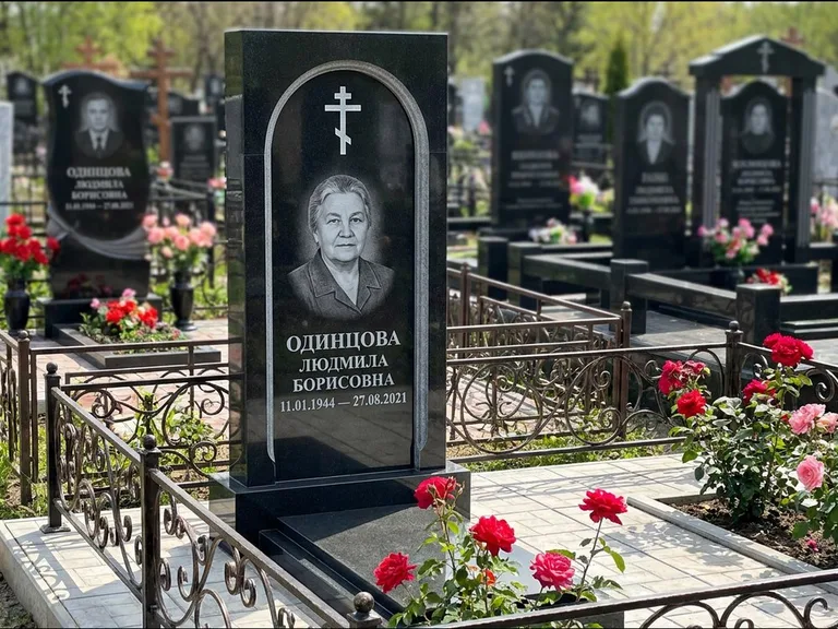 Памятник из чёрного гранита — скромная невысокая стела с крестом с терновым венцом, работа «Лаврентьева» в Барнауле