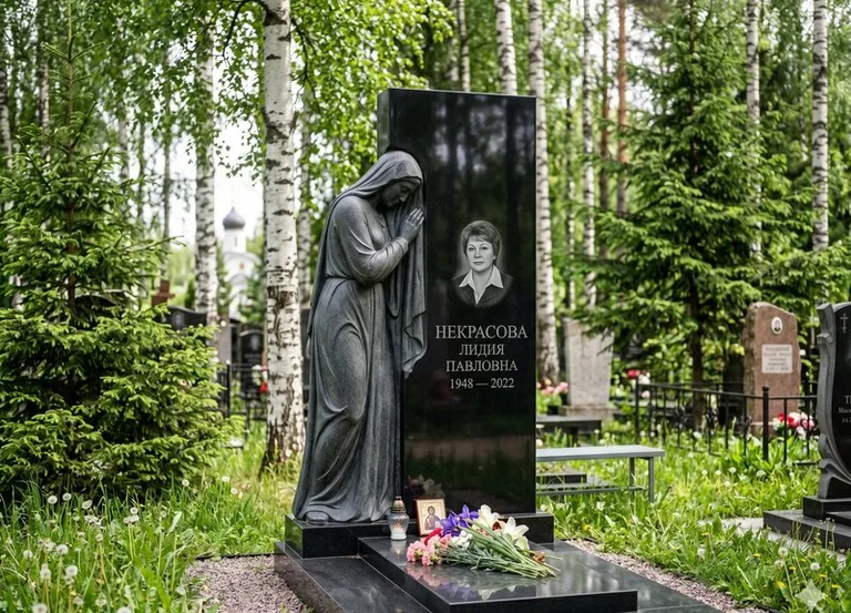 Гранитная фигура скорбящего мужчины у чёрной стелы в Барнауле